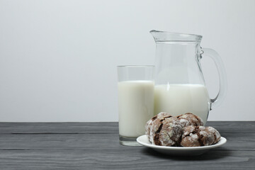 glass and jug with milk, cookies on grey wooden background