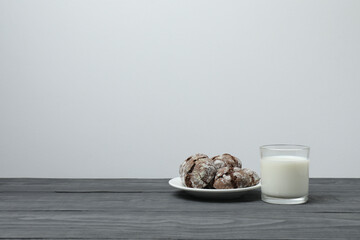 glass with milk and cookies on grey wooden background
