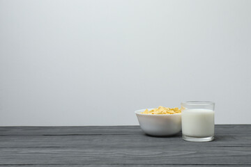 glass with milk, cornflakes on grey wooden background
