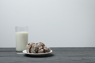 glass with milk and cookies on grey wooden background
