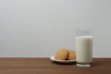 glass with milk and cookies on wooden background