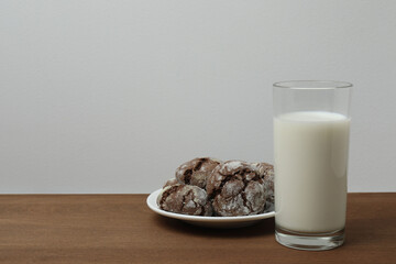glass with milk and cookies on wooden background