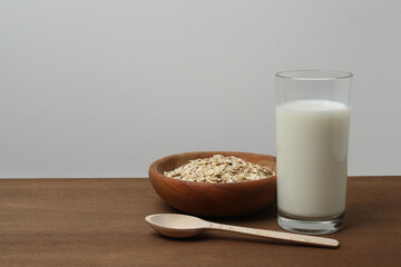 glass of oat milk and oatmeal on a wooden table.