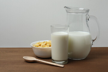 glass and jug with milk, cornflakes on wooden background