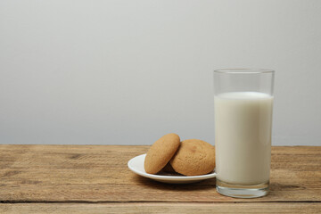 glass with milk and cookies on wooden background