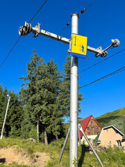Ski lift tower with safety sign on a snowless summer slope
