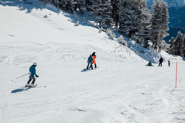 Snowboarders and skiers ski in the resort on the slopes