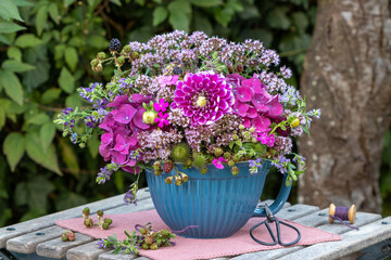 Blumen-Arrangement mit pink Dahlie, Hortensienblüten,  Feldthymian und Brombeeren im Porzellantopf...