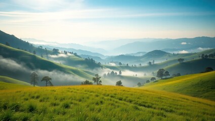 Fototapeta premium A scenic view of rolling green hills and mountains with a light mist in the valleys under a clear blue sky.