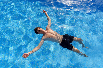 Relaxing tourist floating in azure pool, basking in warm sunlight during tropical getaway