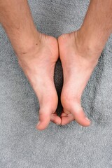 Close-up of bare feet resting on a gray towel. Relaxing and peaceful.