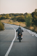 Obraz premium Motorcyclist riding on country road during sunset