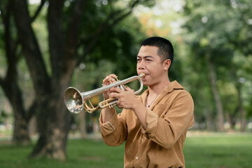Musician performs with trumpet in a green public park