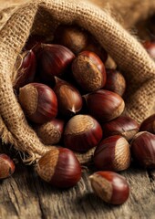 Rustic burlap sack spilling glossy fresh chestnuts onto rough wooden surface, warm earthy tones perfect for autumn harvest, organic food, countryside or cozy seasonal compositions.
