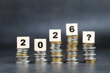 Stack of coins with wooden blocks, symbolizing future financial growth, economic uncertainty, and...