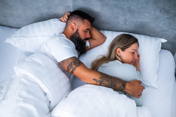 Young married couple is sleeping in their bed. They are embracing and enjoying good sleep.