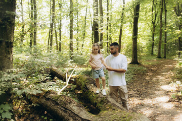 Father and Daughter Exploring a Forested Trail Together on a Sunny Day
