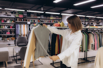 Obraz premium Woman Shopping in Stylish Clothing Store Browsing for Trendy Outfits and Accessories