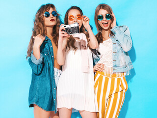 Three young beautiful smiling hipster female in trendy summer dresses and sunglasses. Sexy carefree...