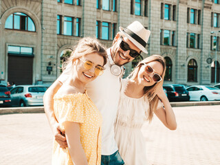 Group of young three stylish friends posing in the street. Fashion man and two cute female dressed...
