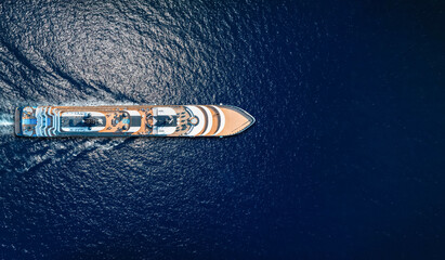 Aerial overhead view of a luxury cruise ship or luxury yacht sailing over sparkling, blue ocean as a travel concept with copy space<