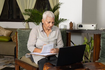 Matured woman with cancer working on laptop at home