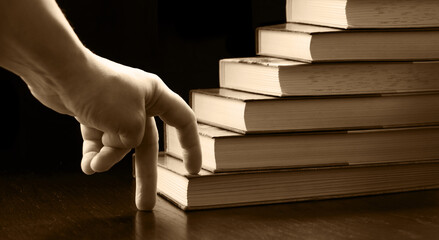 Hand walking on a ladder made of books
