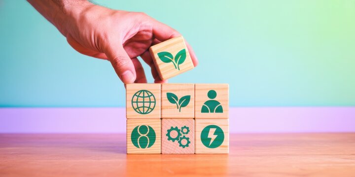 Hand stacking wooden blocks with sustainability icons to represent sustainable living and environmental responsibility.