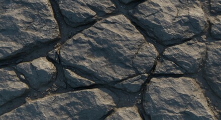 Topdown view of dark grey weathered rock formations with prominent cracks and shadows illuminated by sunlight