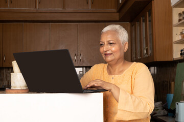 Portrait of Indian senior woman using laptops during tech skill session at home