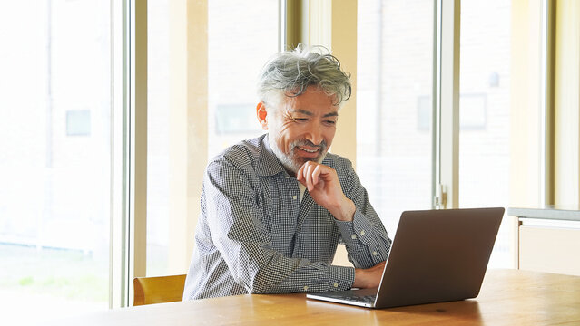 リビングでノートパソコンを使うシニア男性