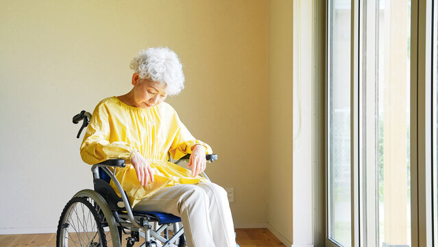 車椅子に乗ってぐったりするシニア女性
