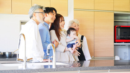 Smiling three-generation family surrounding a baby