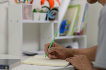 Person Writing in Notebook with Colorful Plants in Background