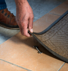 A person getting a key from under their mat