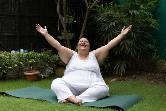 Oversized woman laughing spreading hands, relaxing doing yoga at park. Retirement life. Mental health and fitness, Stress free, Fun activity. laugh of therapy senior living - Powered by Adobe