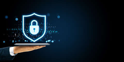Digital shield with padlock icon floating over tablet in business hand on dark background symbolizing cybersecurity and data protection concept.