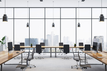 Modern open office interior with wooden desks, black chairs, computers, and panoramic city view...