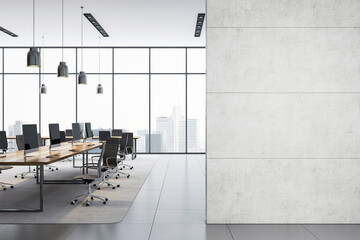 Modern empty office interior with row of desks and large blank concrete wall for poster or logo...