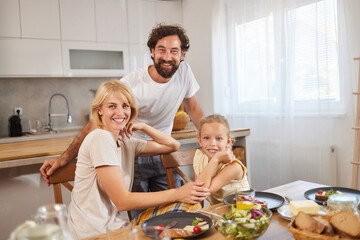 A family gathers around a table filled with delicious food, sharing a moment of happiness and connection during breakfast together in a bright dining space.