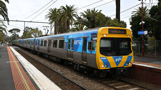 Yellow and blue Comeng train, operated by Metro Trains Melbourne, as it pulls into Ripponlea Railway Station on a cloudy day