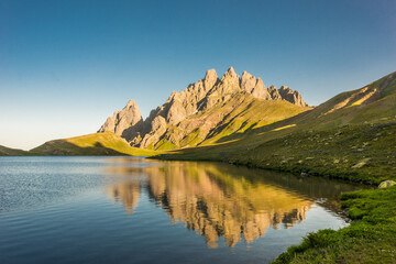 Stunning view of rocky Caucasus mountain peaks reflecting perfectly on a calm alpine lake at...