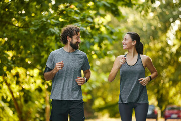 Two people run side by side on a sunny morning. Their smiles reflect their enjoyment of staying...