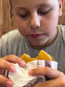 A 10-year-old boy eagerly eats a McDonald's burger. Concept of child nutrition and fast food.
