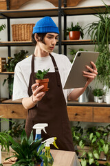 Young man tending to plants while using a tablet in a stylish indoor garden studio