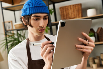 Young man engaged in planting tasks while attentively using a digital tablet indoors