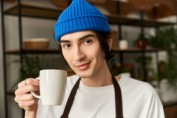 Handsome young man enjoys a warm drink while working with plants in a cozy studio environment