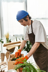 Handsome young man nurturing plants while transplanting in a bright studio space