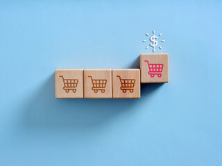 Shopping cart icons on wooden blocks leading to dollar sign representing online shopping and e-commerce business