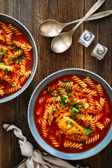 Tomato soup with chicken thigh and noodles on wooden table